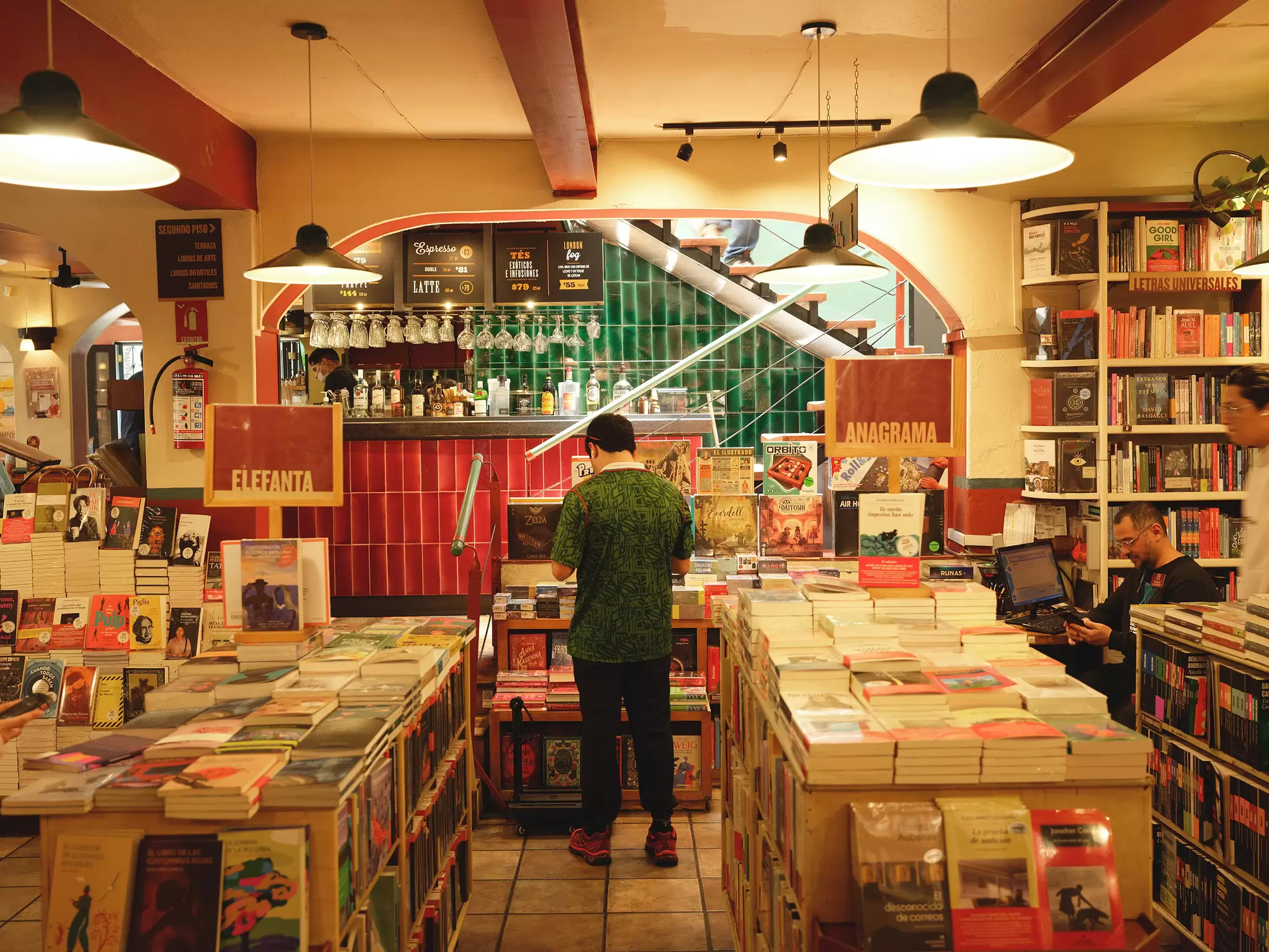A patron at a bookstore in front of a display; tables of books are in the foreground.
