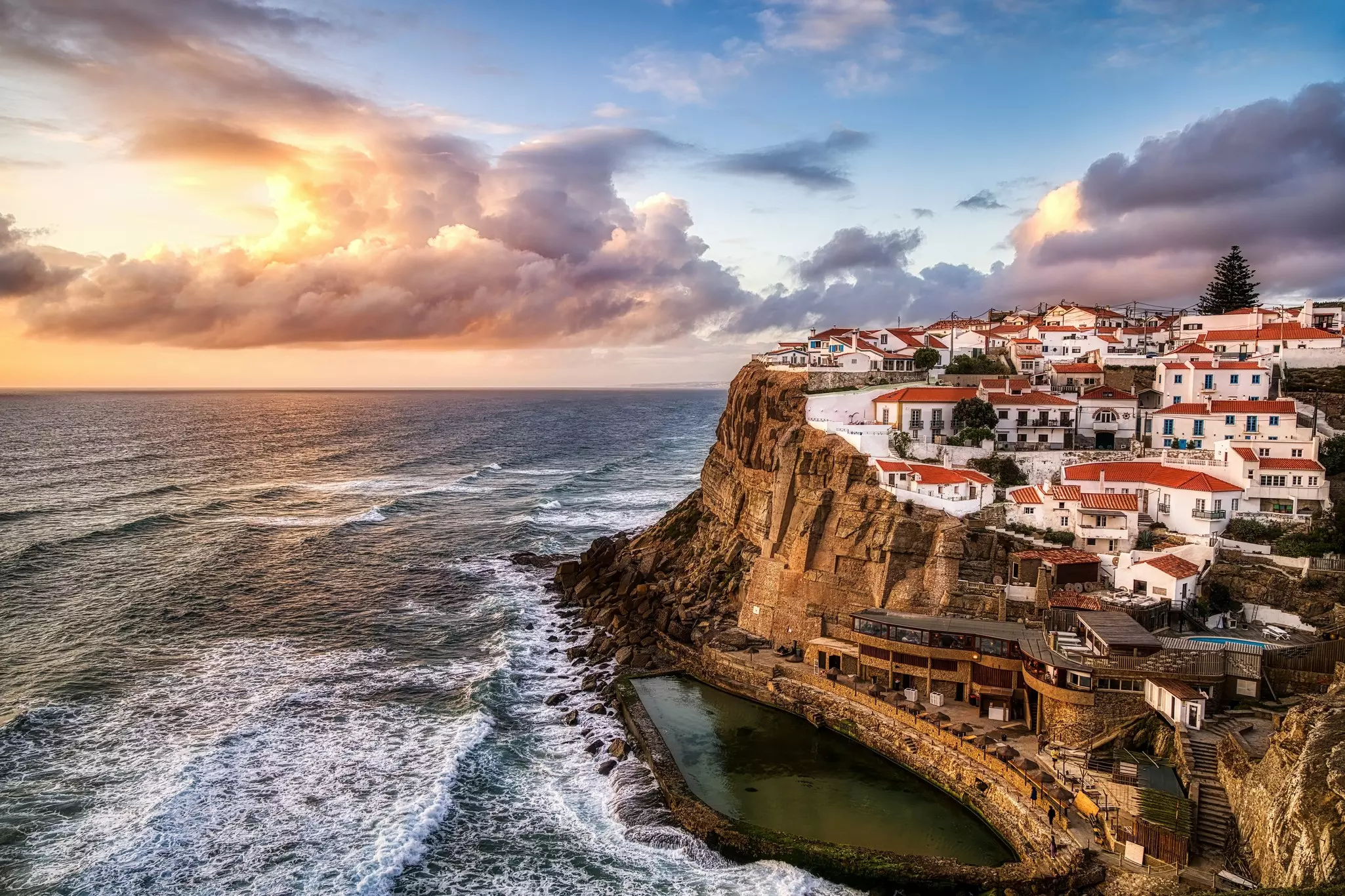 The sunset over the sea viewed from a clifftop village of white buildings with red roofs