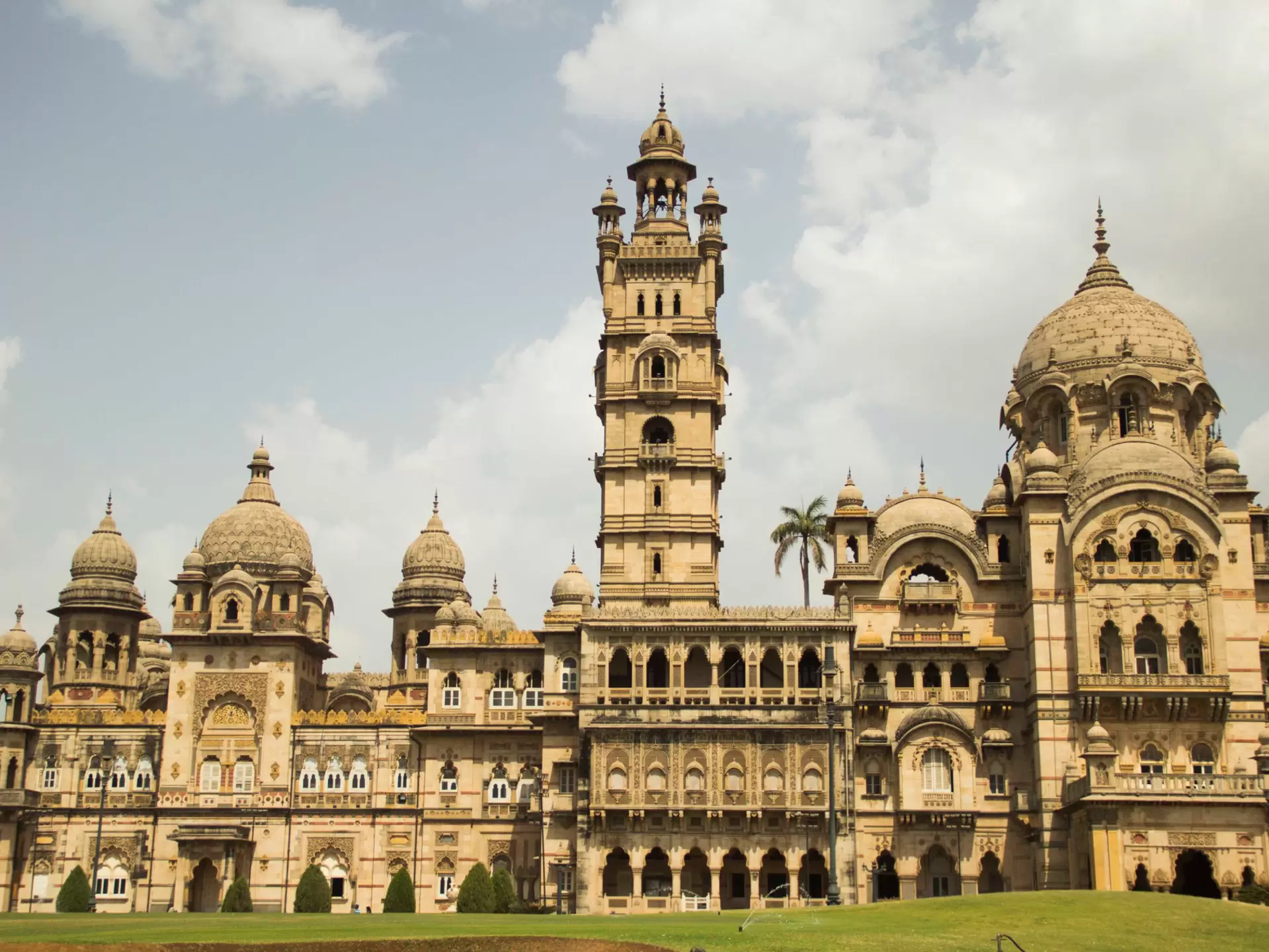 The facade of a palace has multiple domes, balconies, a tall tower, and other elaborate architectural elements, Vadodara, Gujarat, India