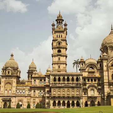 The facade of a palace has multiple domes, balconies, a tall tower, and other elaborate architectural elements, Vadodara, Gujarat, India