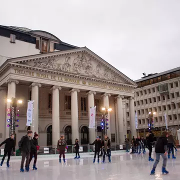 Ice-skaters on a rink in front of a building with columns in central Brussels.