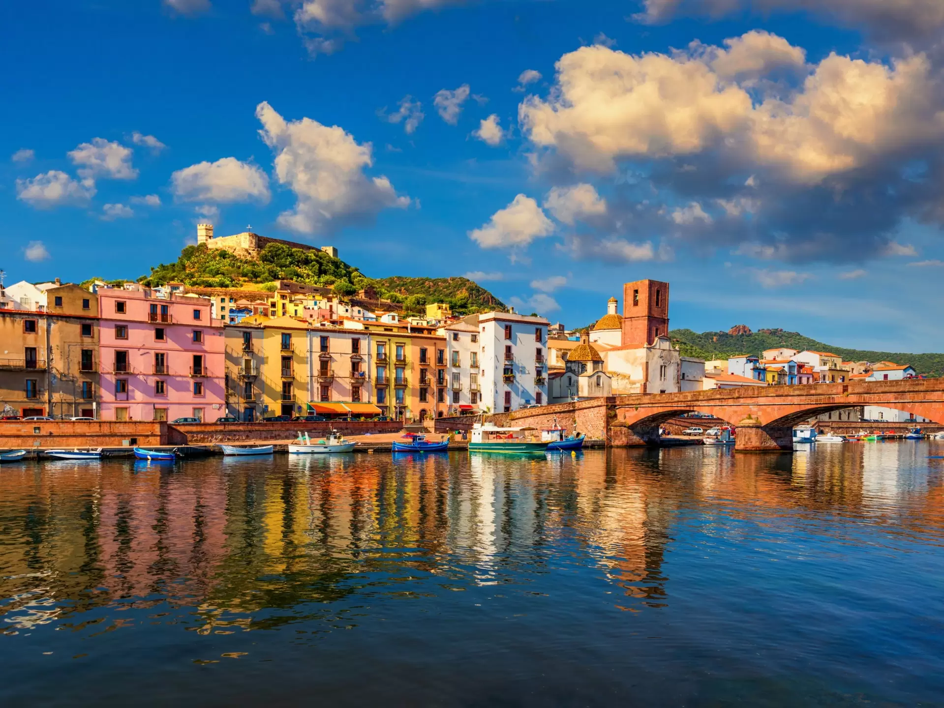 Colorful buildings lining a riverside and an ornate bridge over the water