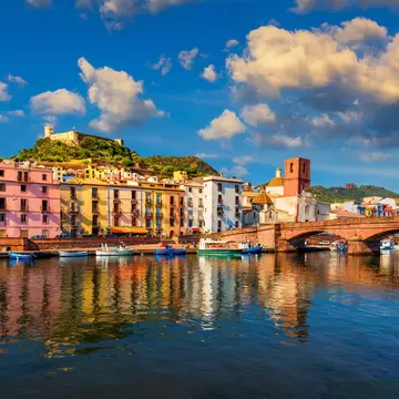 Colorful buildings lining a riverside and an ornate bridge over the water