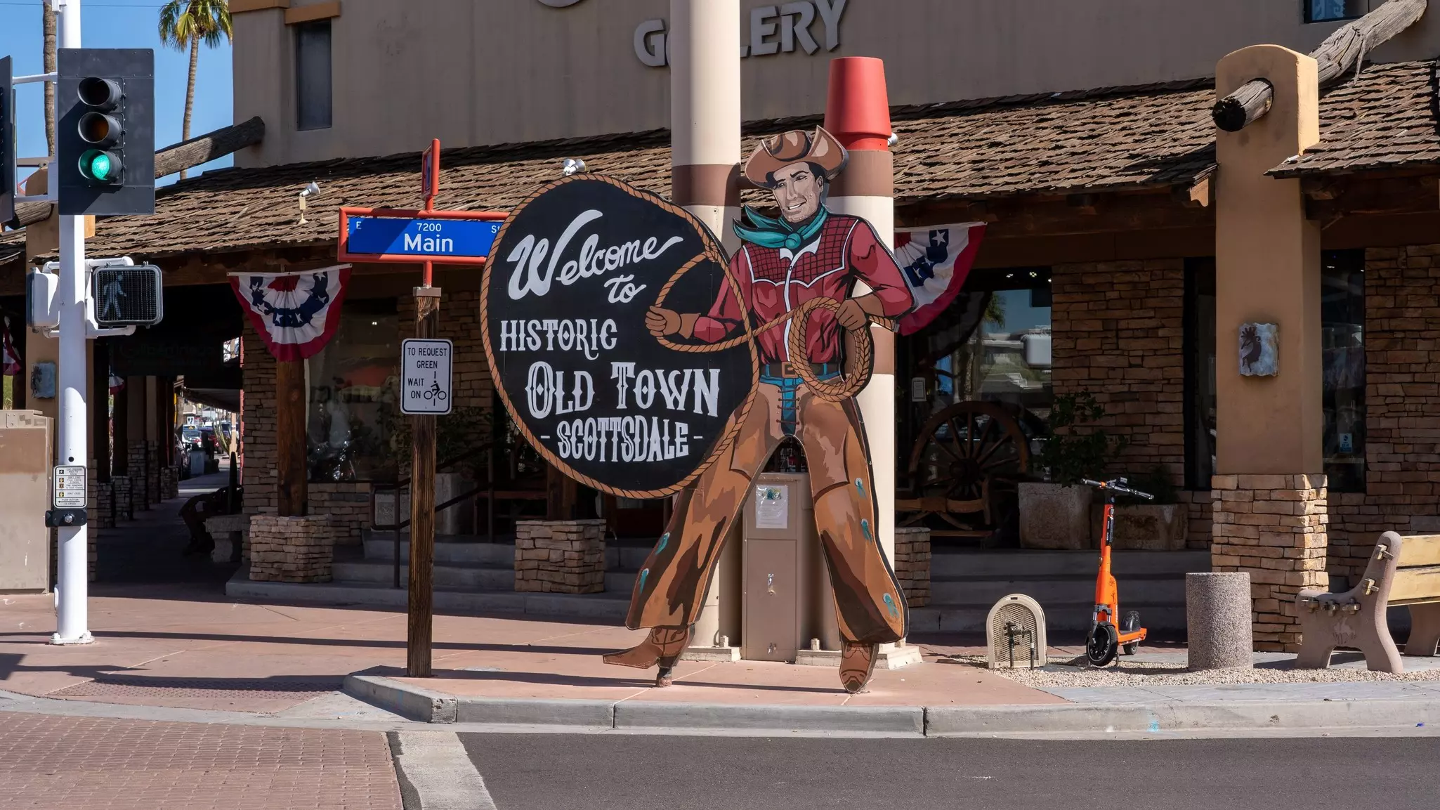 A cowboy sign in front of Main Street in Old Town Scottsdale