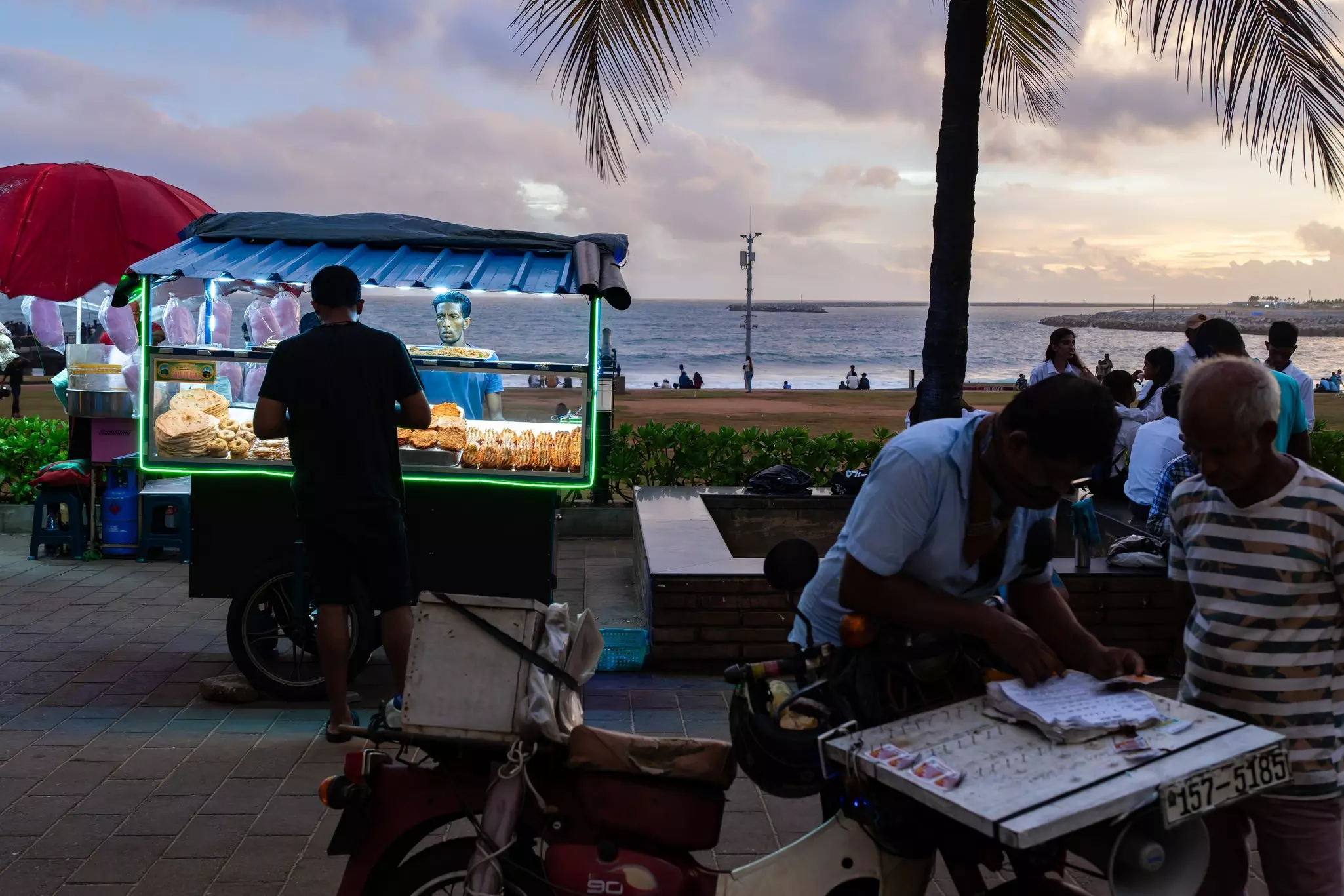 A food stand with different bread products behind a screen on a beach at dusk.