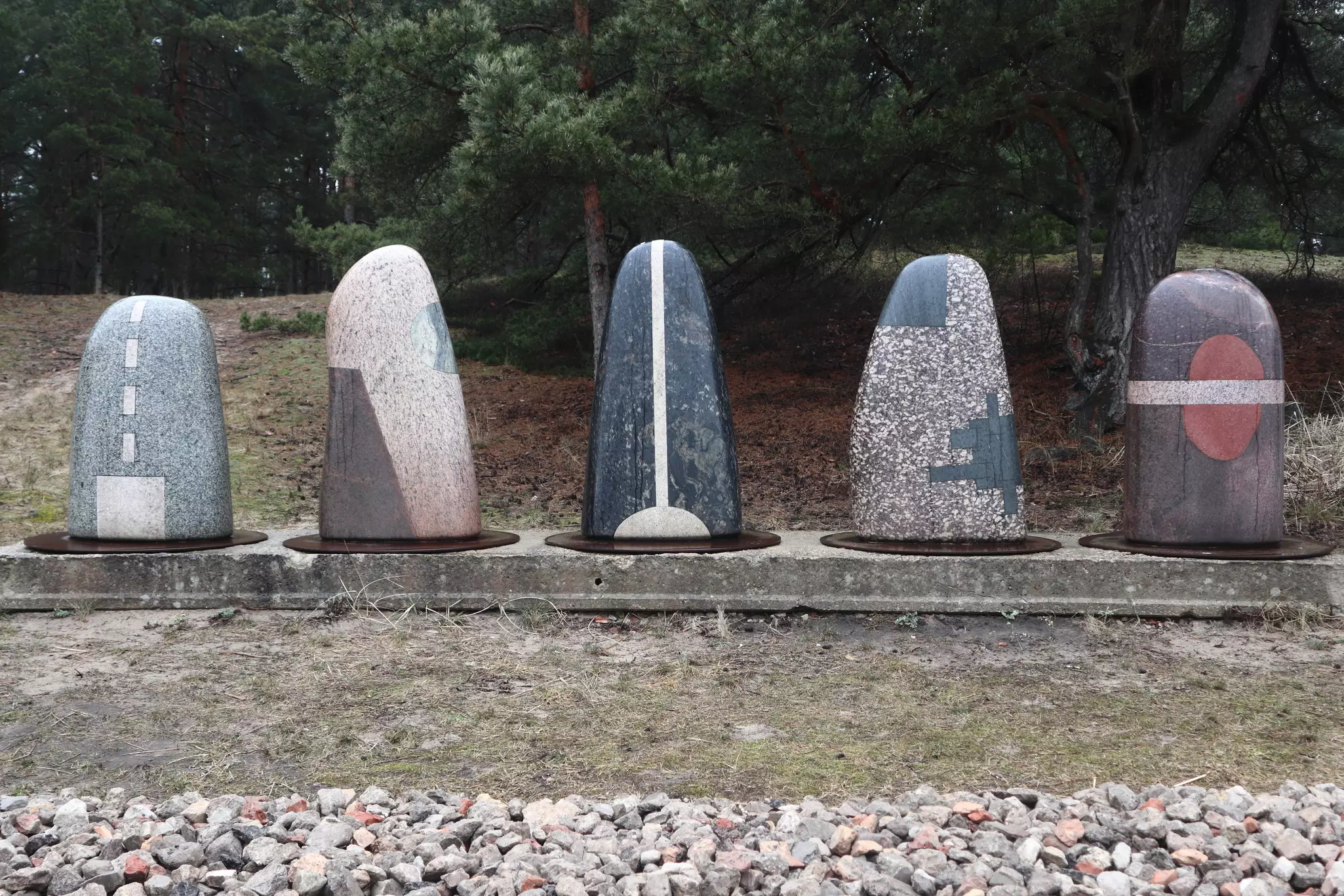 Smooth stone sculptures line a path along a river.