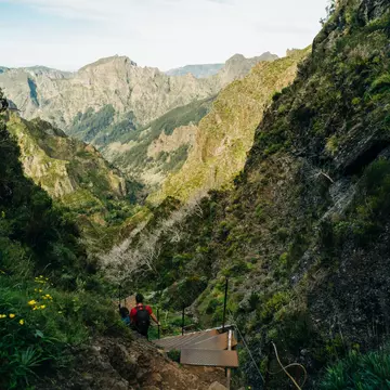 Hikers walk down makeshift steps on a trail through a mountainous landscape.