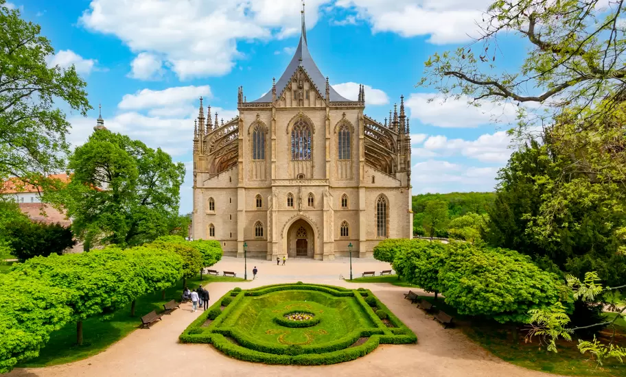 St Barbara's Church in Kutná Hora with its Gothic west front and tent-like roof behind a hedged formal garden