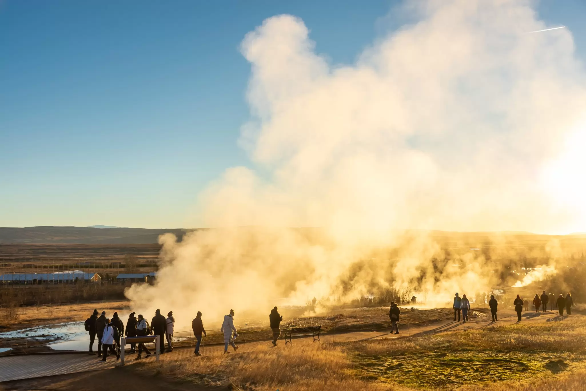 View of the Stokkur geyser erupting in front of a crowd of tourists in Iceland.