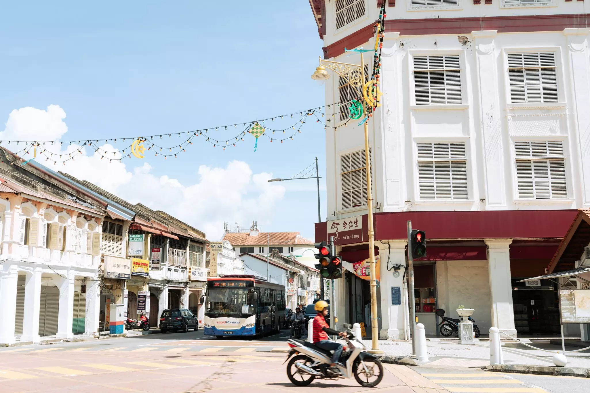 A man on a motorbike drives past a historic building on a city street.