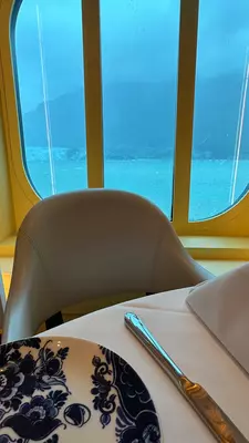 Interior of a ship's dining room looking out on the ocean beyond.