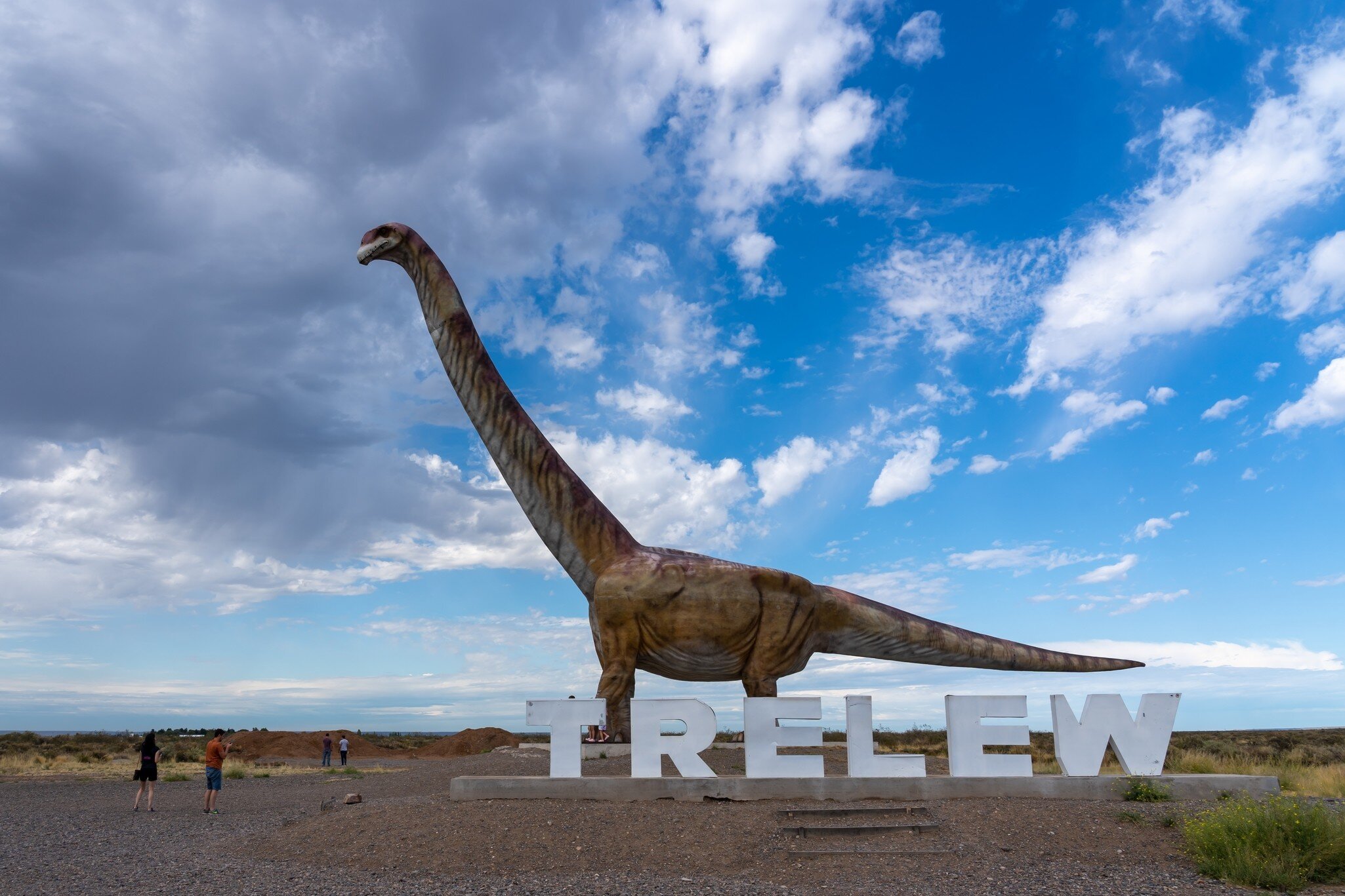  Visitors watching the replica of Titanosaurus with Trelew sign near Museo Paleontologico Egidio Feruglio (MEF) in Trelew, Chubut Province, Argentina.
