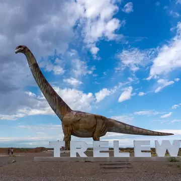 Visitors watching the replica of Titanosaurus with Trelew sign near Museo Paleontologico Egidio Feruglio (MEF) in Trelew, Chubut Province, Argentina.