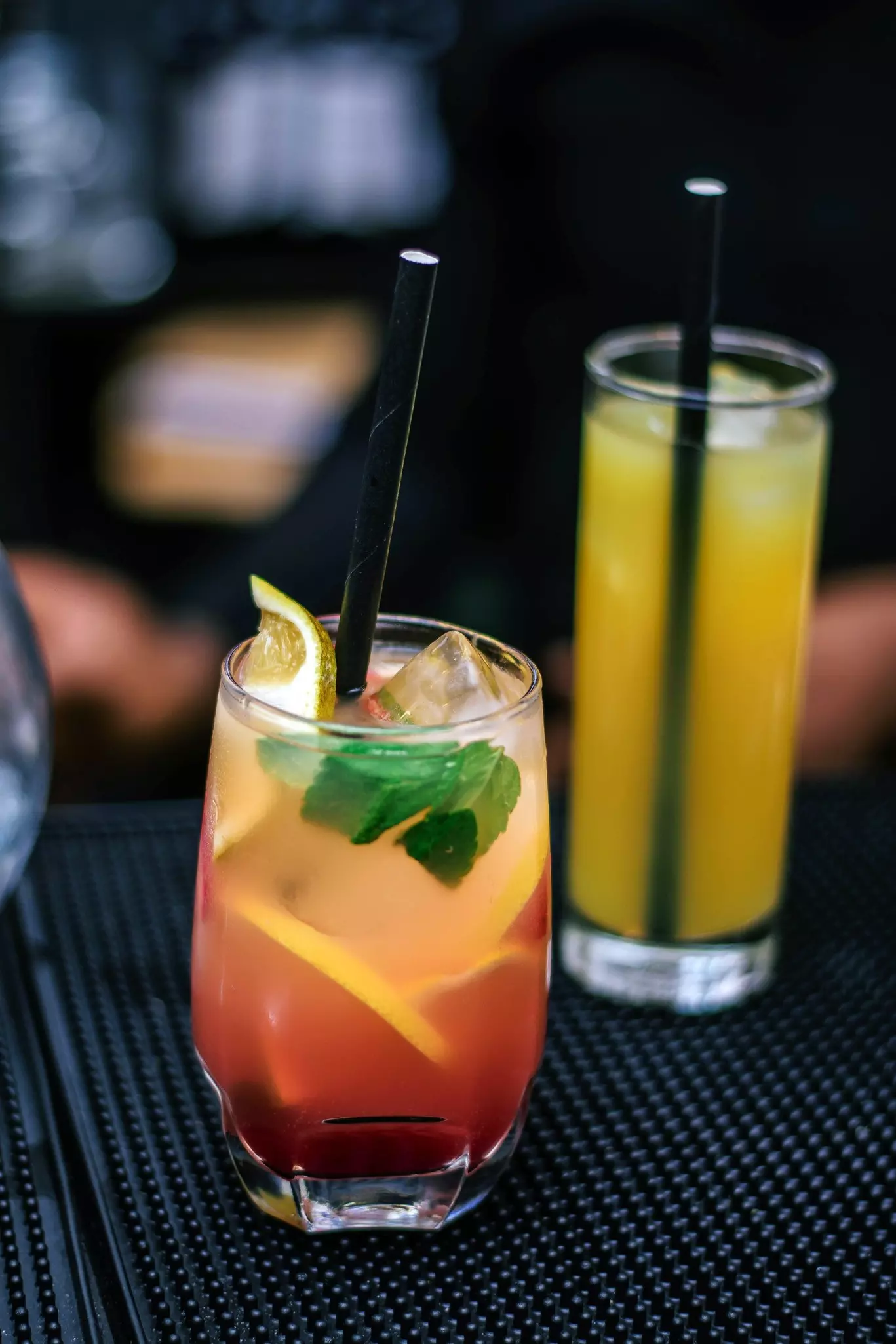 A yellow cocktail in a glass on a bar.