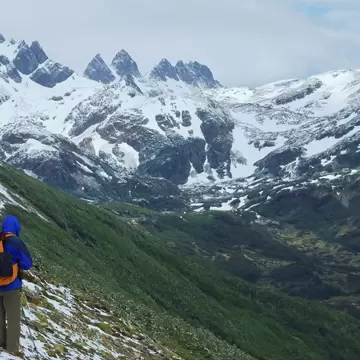 A lone hiker on the remote Dientes Circuit, surrounded by mountain peaks covered in snow in Chile