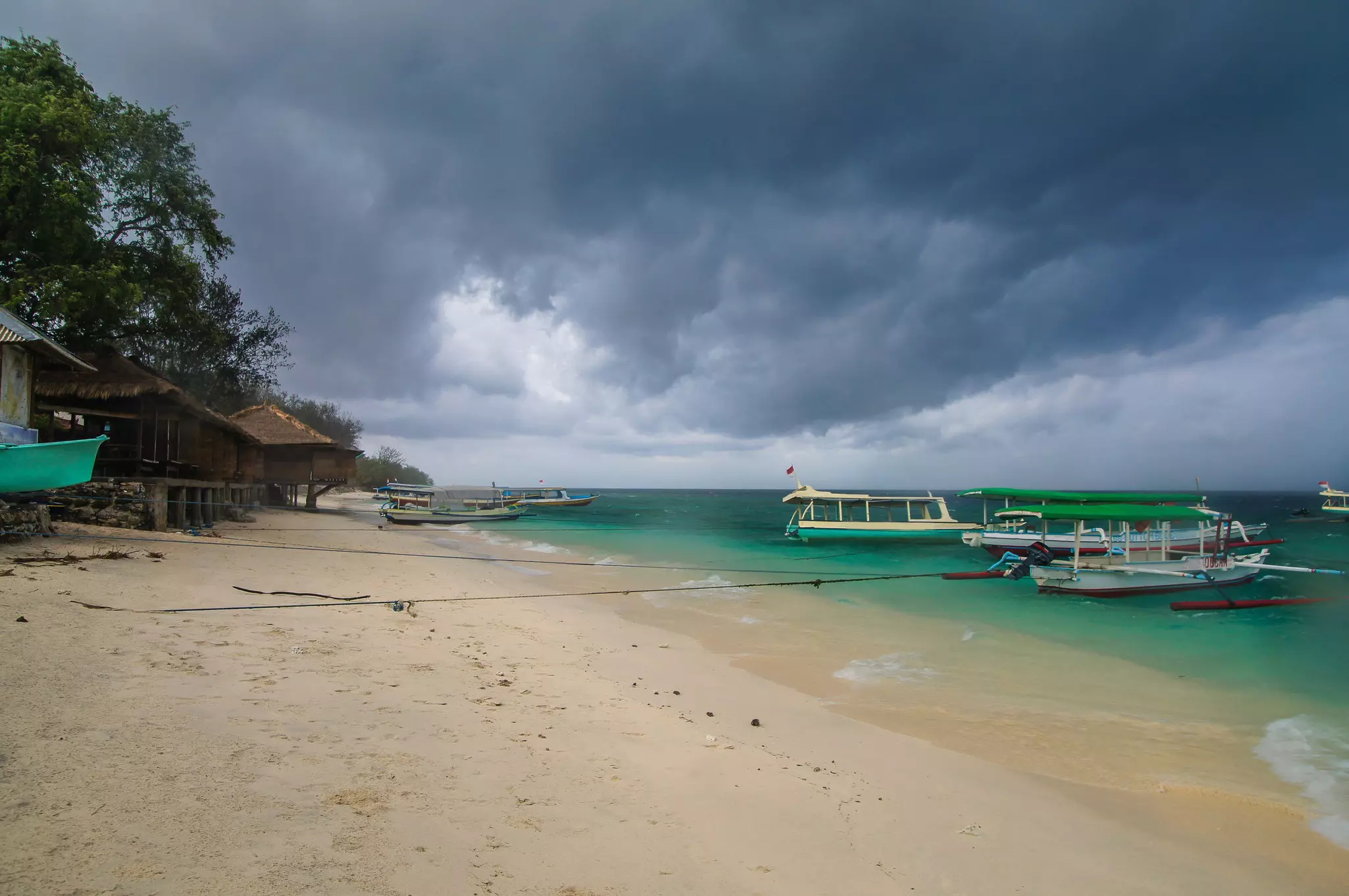An empty tropical beach with dark clouds overhead.