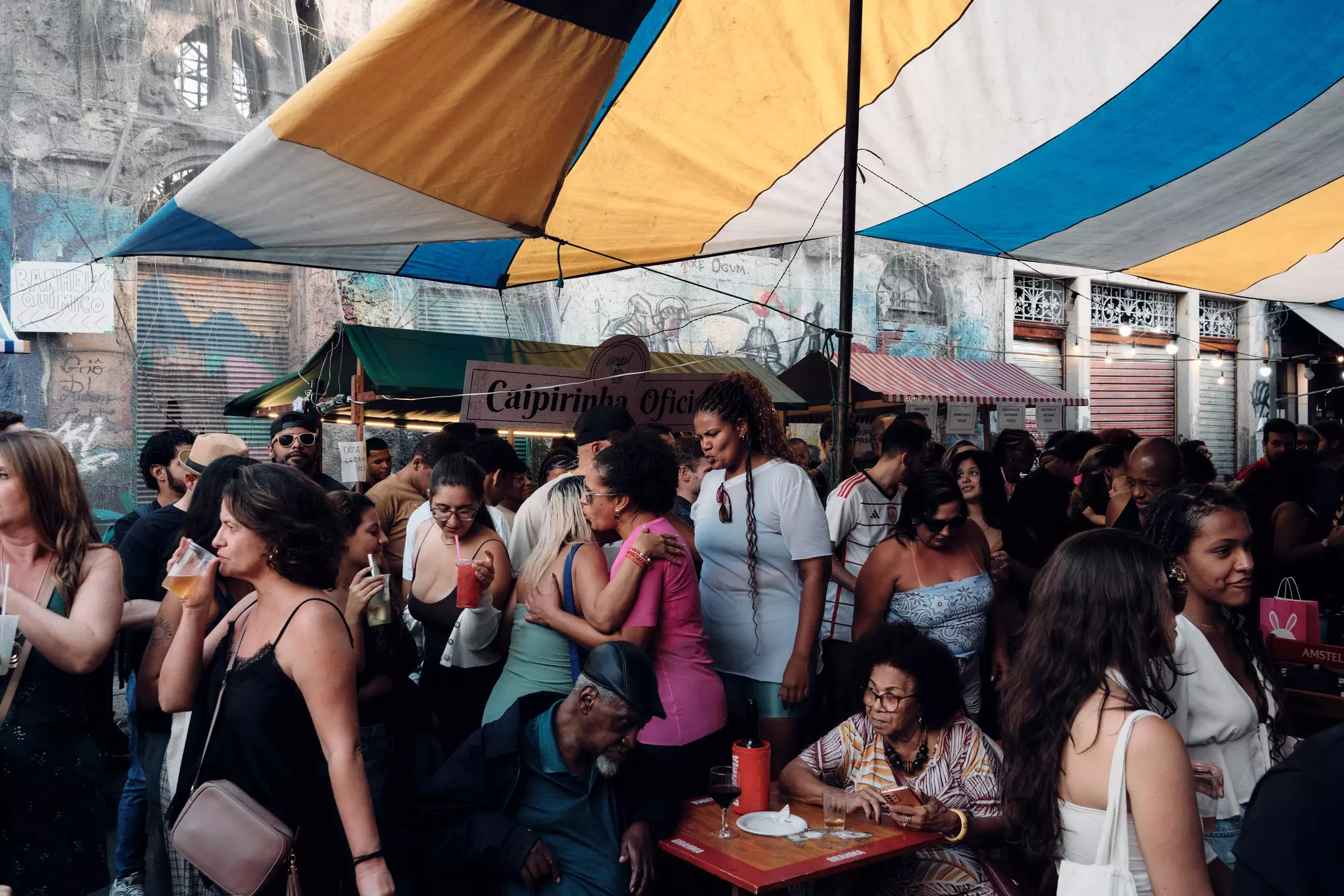 A large group of people outside on a street drinking and chatting.