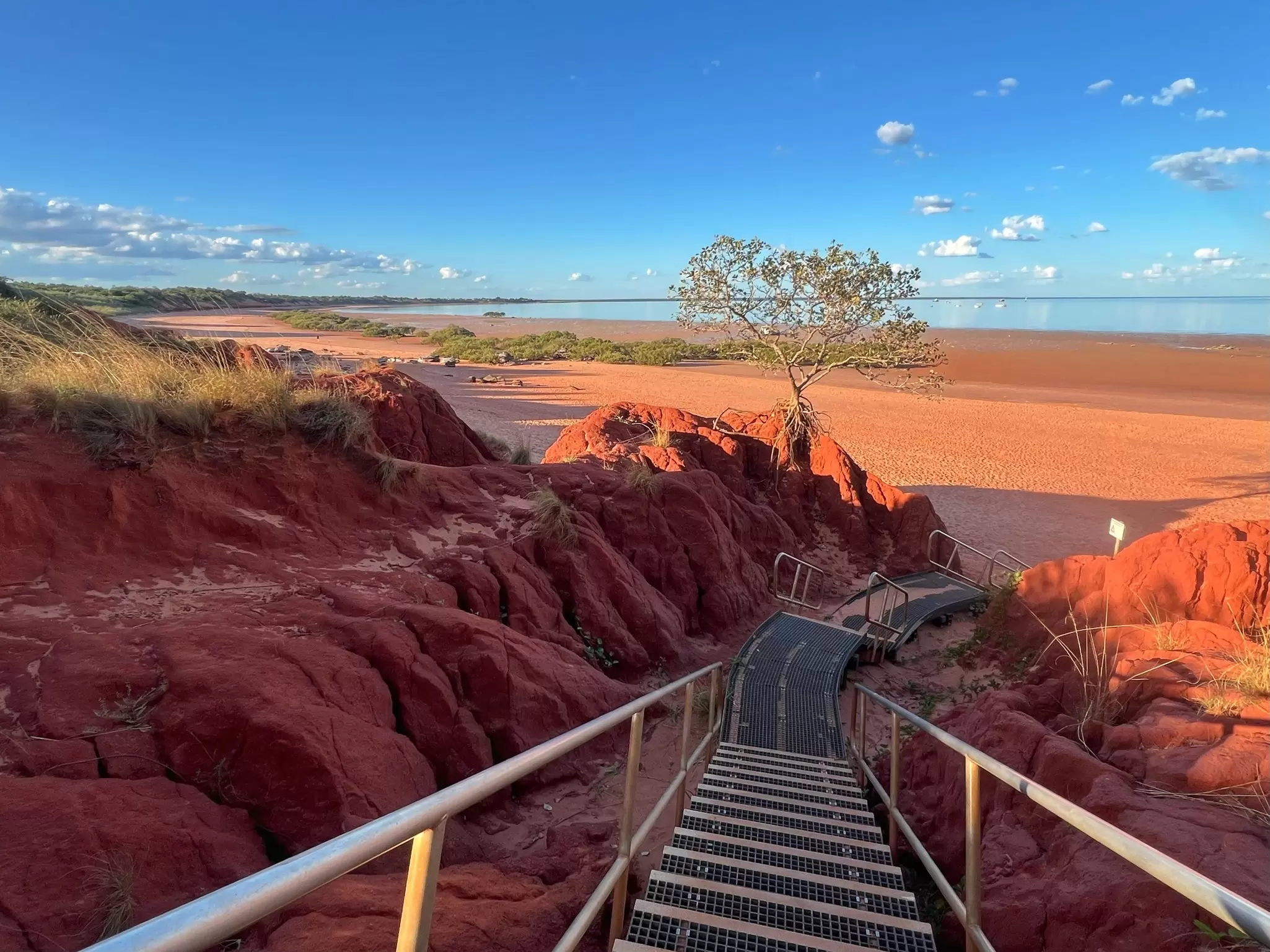 A set of stairs leads to a red sand beach.