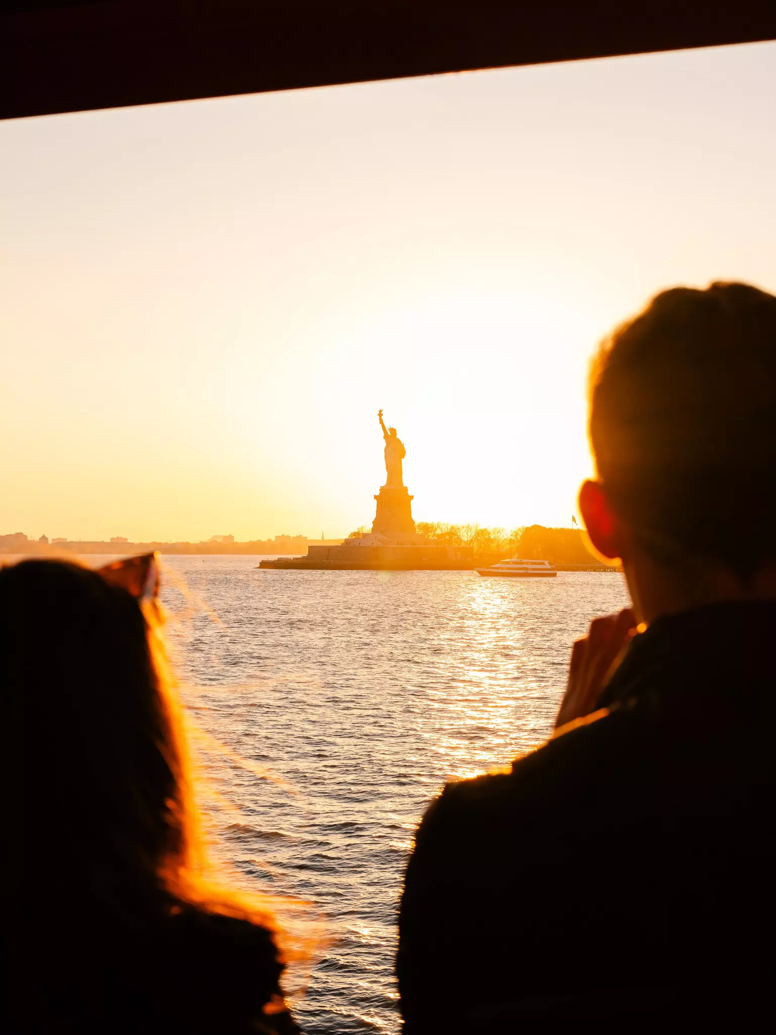The Staten Island Ferry from Staten Island, NY to Manhattan. Commuters and tourists enjoy the sun setting on the Statue of Liberty.