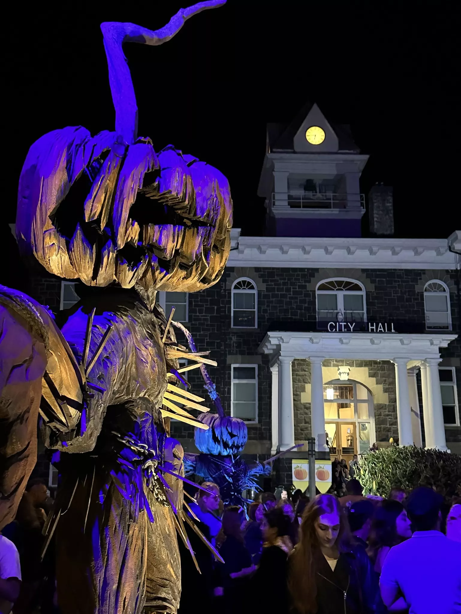 People at a Halloween event at St Helens, with a festive display in the foreground and City Hall in the background