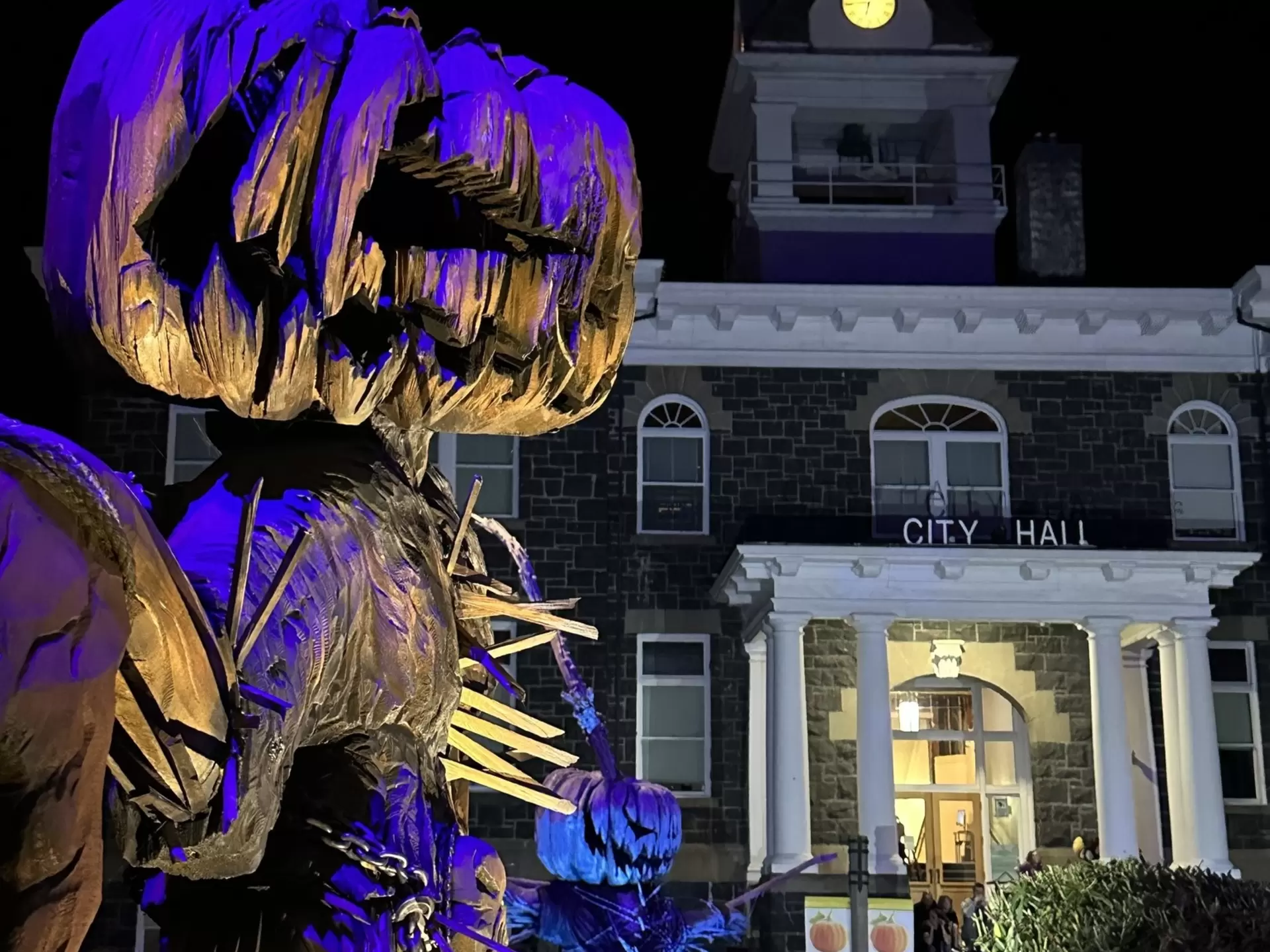People at a Halloween event at St Helens, with a festive display in the foreground and City Hall in the background
