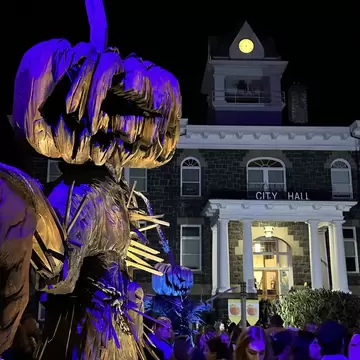 People at a Halloween event at St Helens, with a festive display in the foreground and City Hall in the background