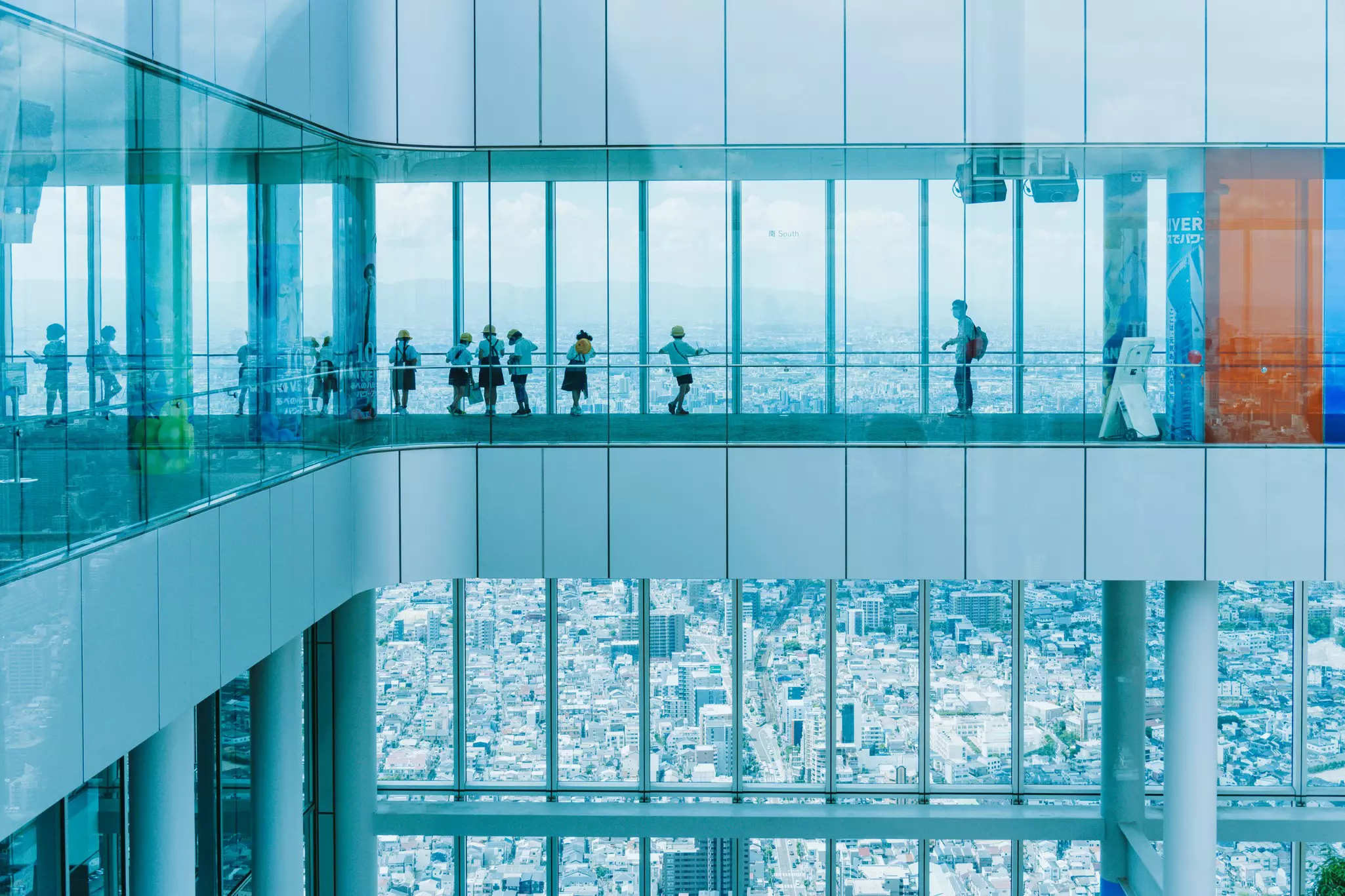 People standing on an observation deck in a building overlooking Osaka and its environs