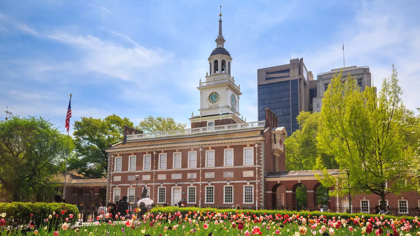 A red-brick building with a white bell tower near a garden of tulips