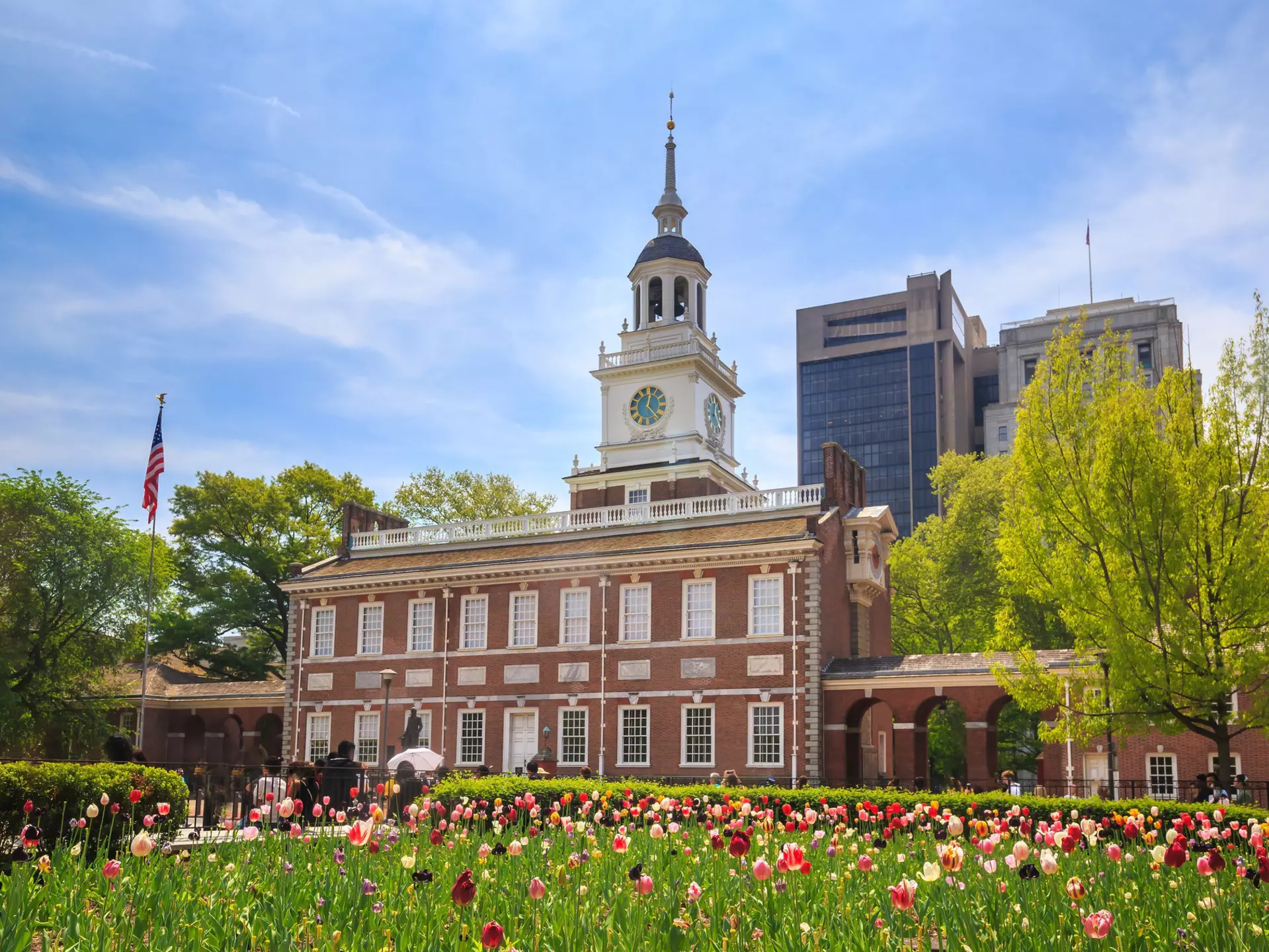 A red-brick building with a white bell tower near a garden of tulips