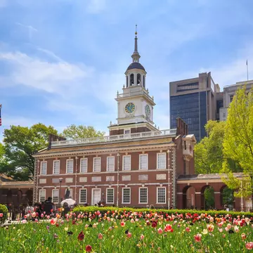 A red-brick building with a white bell tower near a garden of tulips