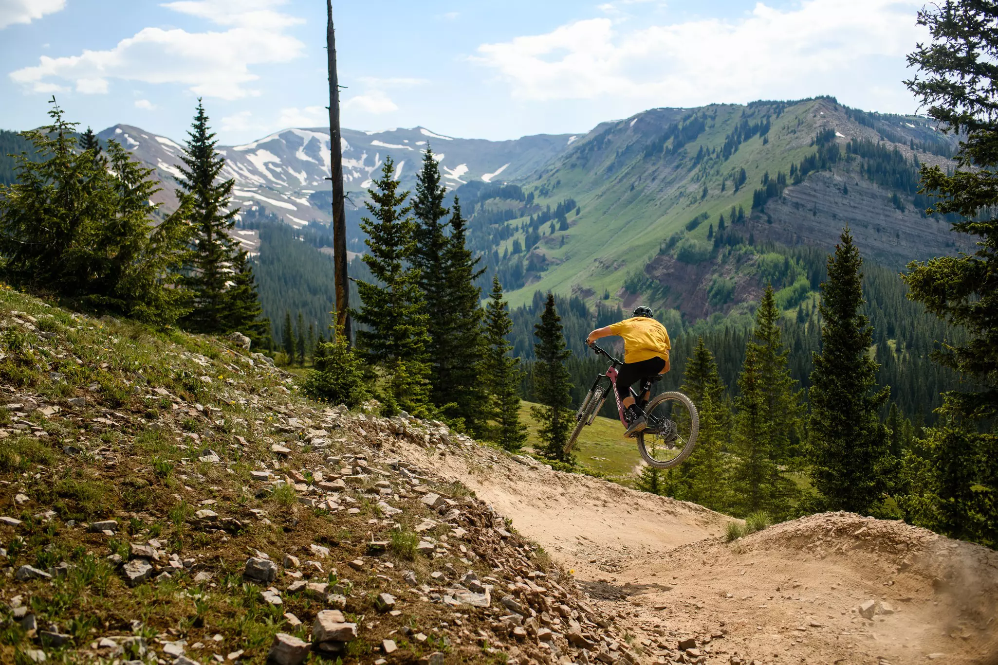 A man on a bike jumps in the air while on a trail.