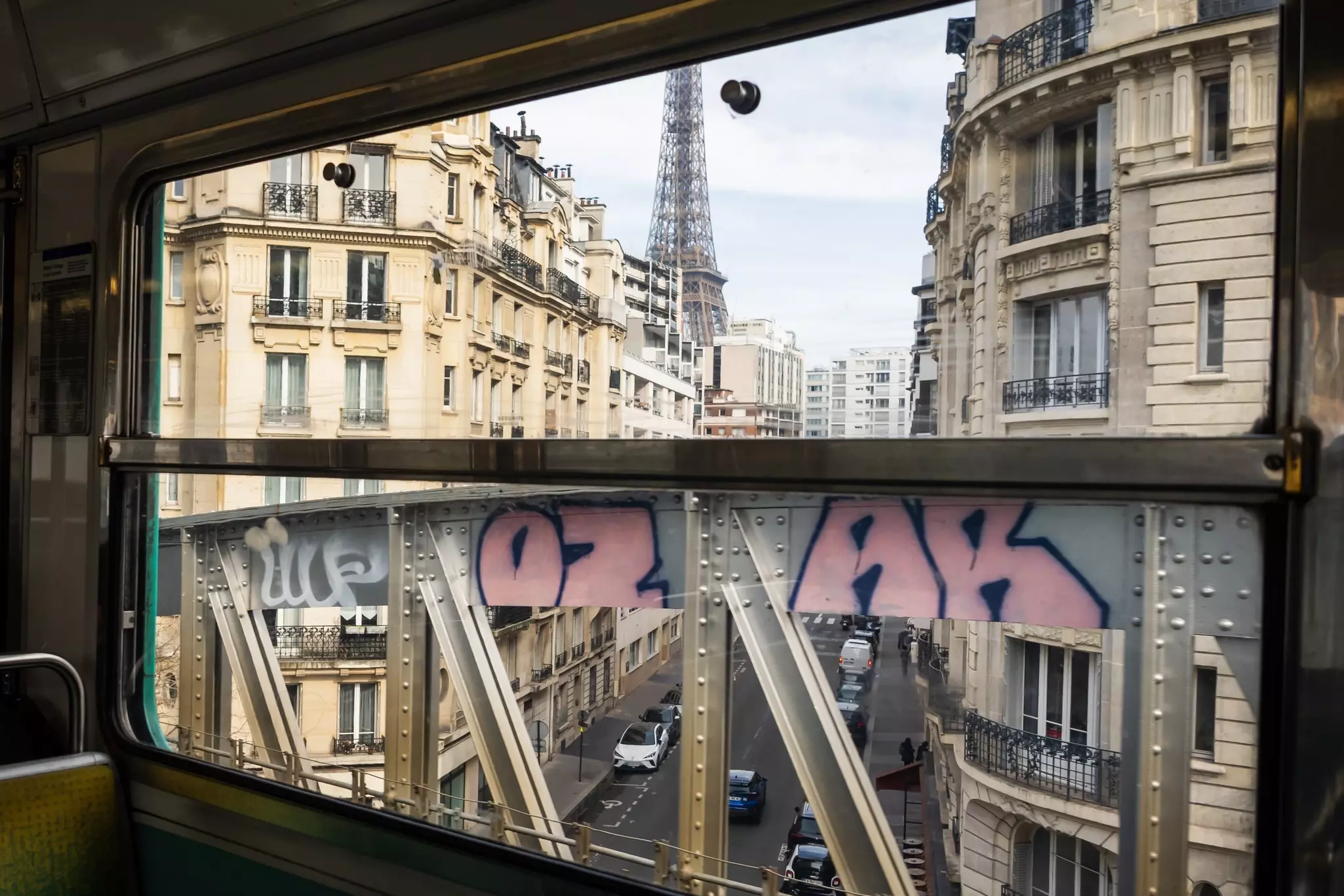 A tall iron structure -- the Eiffel Tower -- seen from a train window