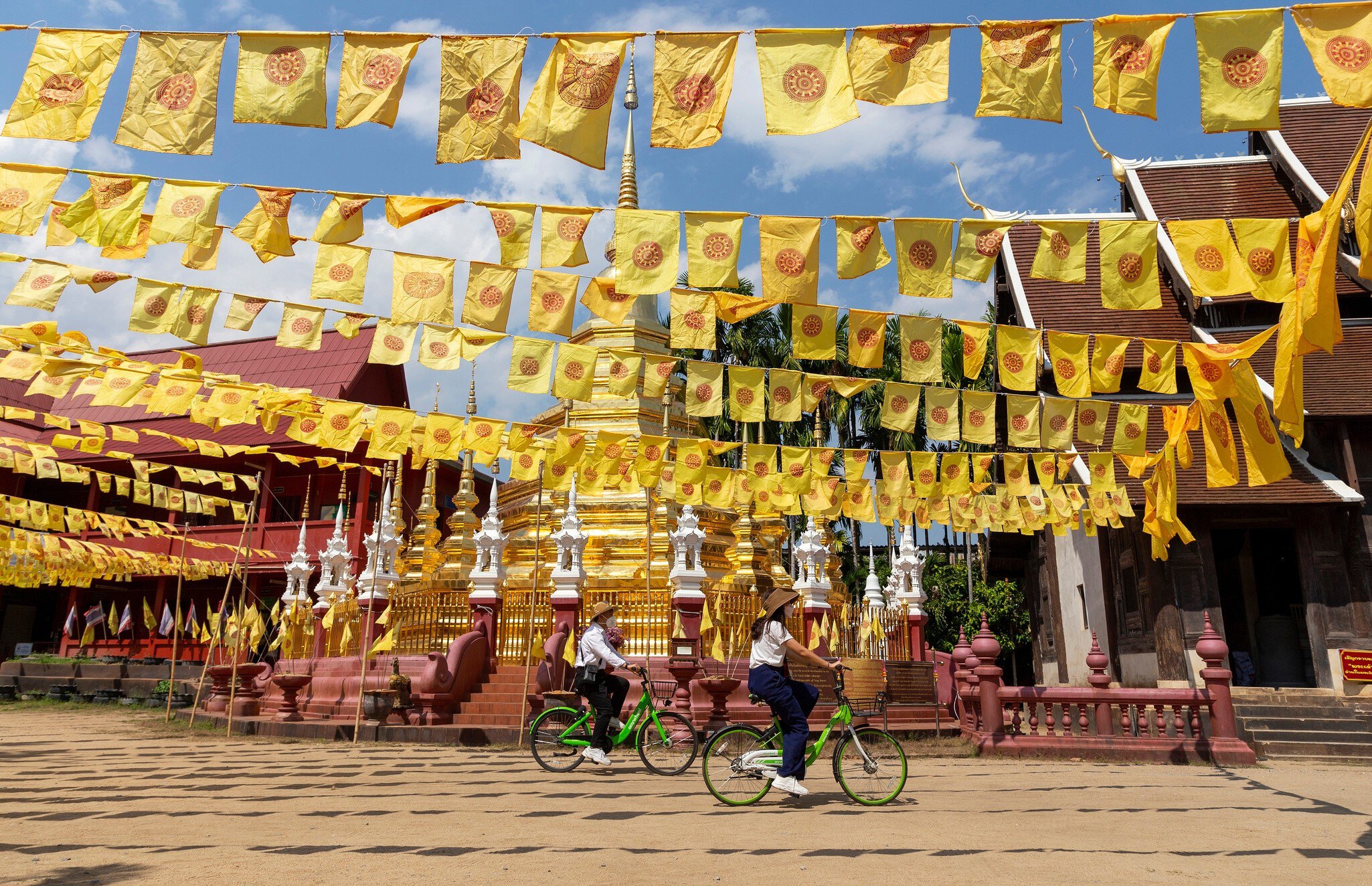 Chiang Mai, Thailand â€“ February 16, 2022: Visitors tourists wearing protective mask cycling past the pagoda in Wat Phan Tao Temple, in Chiang Mai, Thailand. after restarted 'Test and Go' program  License Type: media  Download Time: 2023-11-13T08:30:10.000Z  User: lonelyplanetmedia  Is Editorial: Yes  purchase_order:   