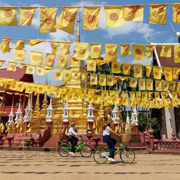 Chiang Mai, Thailand â€“ February 16, 2022: Visitors tourists wearing protective mask cycling past the pagoda in Wat Phan Tao Temple, in Chiang Mai, Thailand. after restarted 'Test and Go' program  License Type: media  Download Time: 2023-11-13T08:30:10.000Z  User: lonelyplanetmedia  Is Editorial: Yes  purchase_order:   