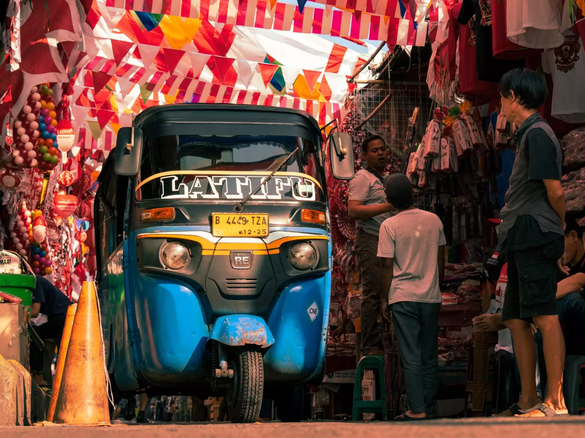 An autorickshaw passes under Indonesian flags in a market in Jakarta, Indonesia. 