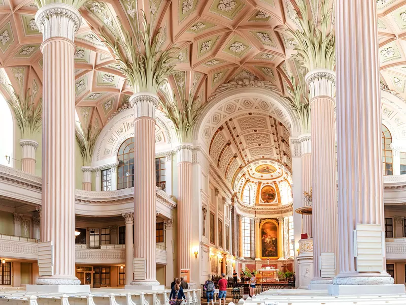Pastel pink interior of the church with large columns and an ornate ceiling