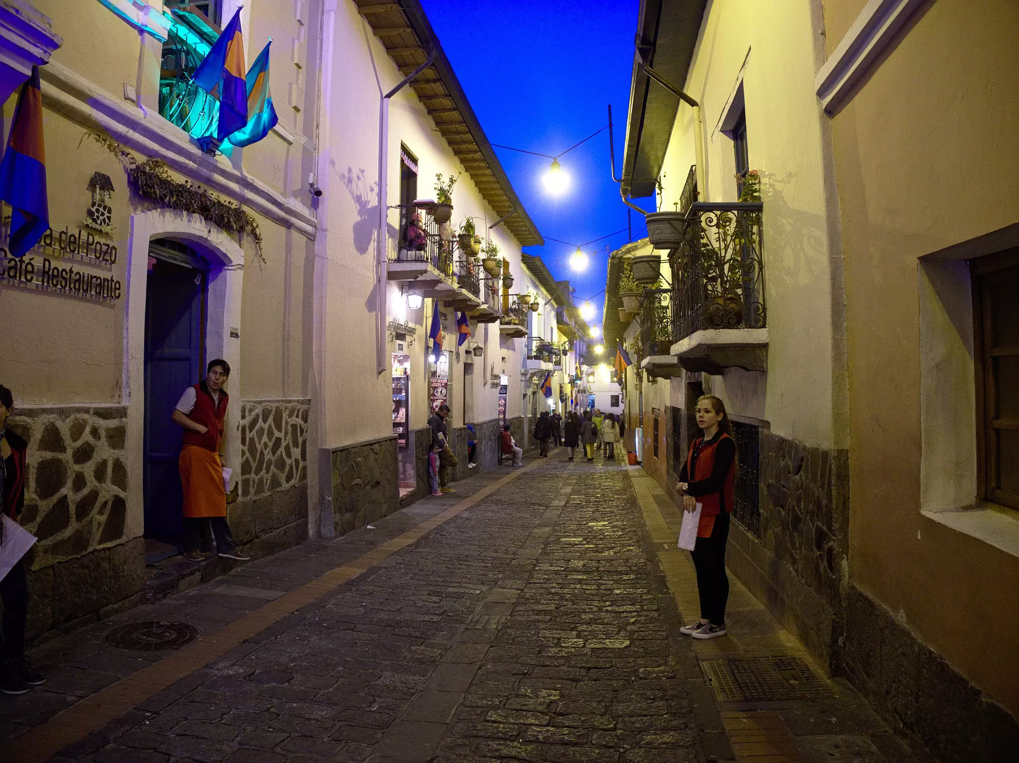 A narrow, cobbled street in a city at dusk.