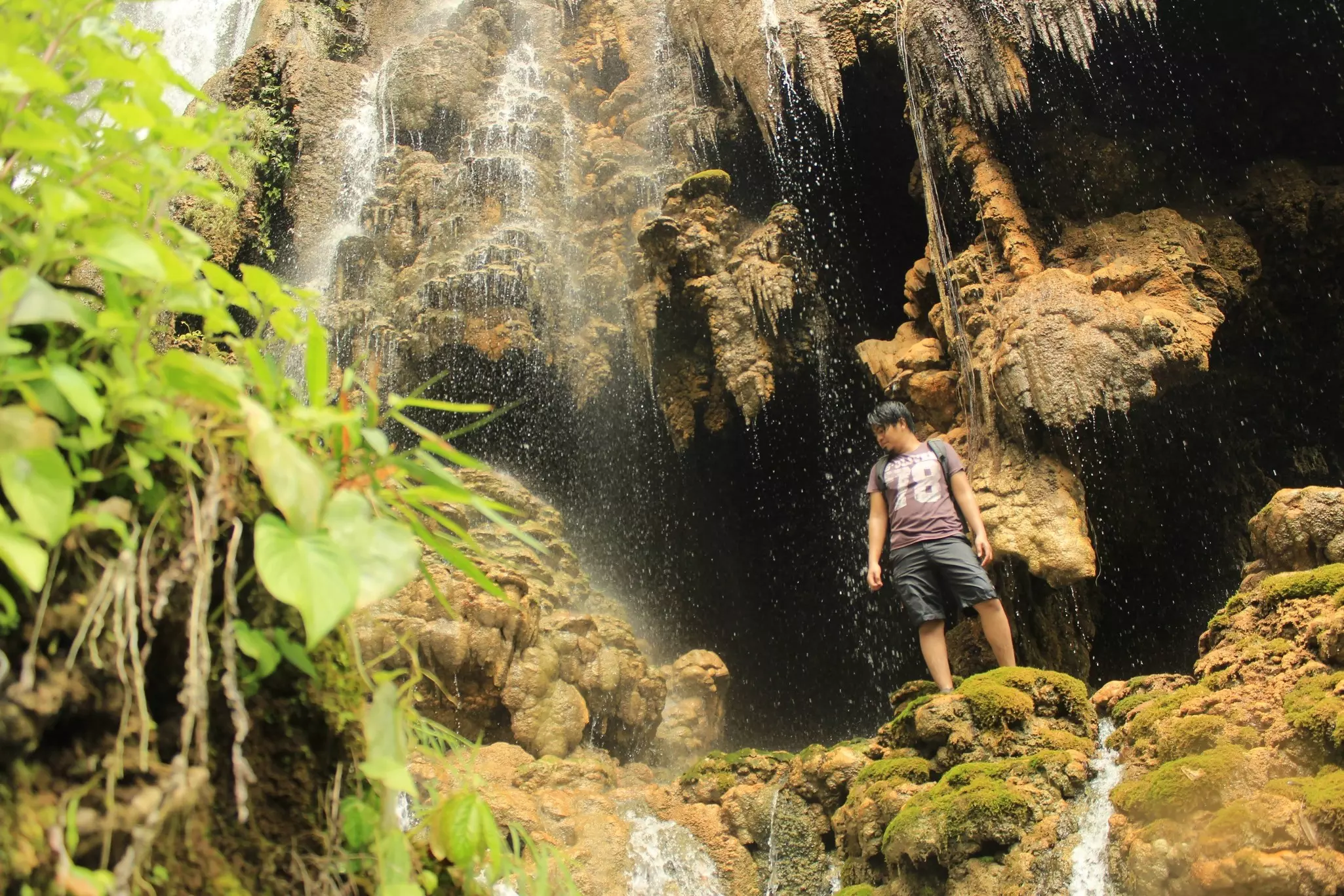 A man stands on rocks in front of caverns eroded by water.