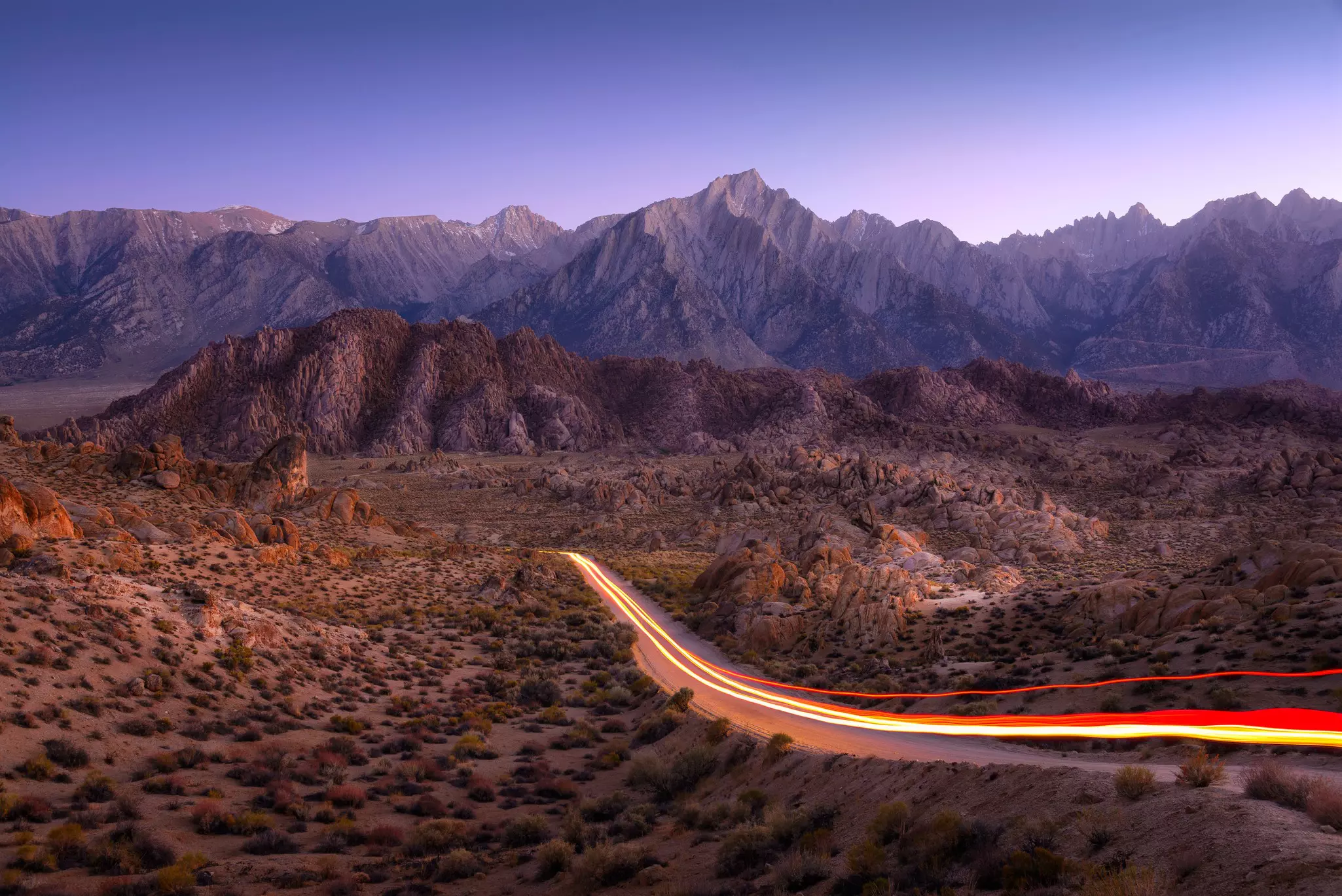 Car lights streaming along a road through the Alabama Hills, California