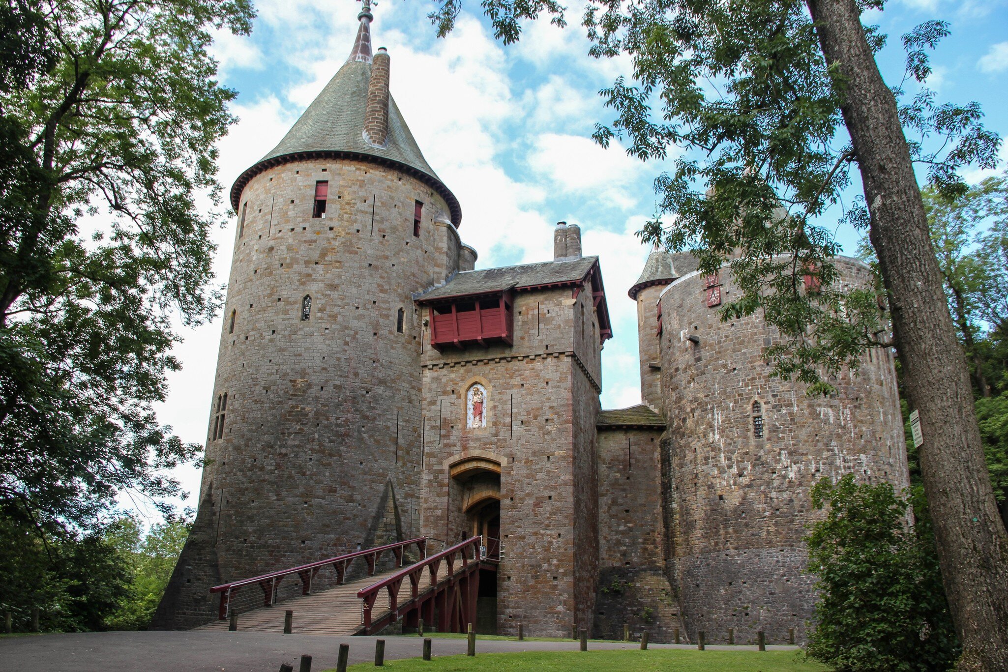 Exterior of Castell Coch in Cardiff, Wales with surrounding greenery and blue cloudy sky.
