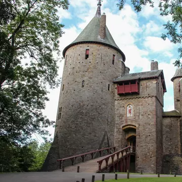 Exterior of Castell Coch in Cardiff, Wales with surrounding greenery and blue cloudy sky.