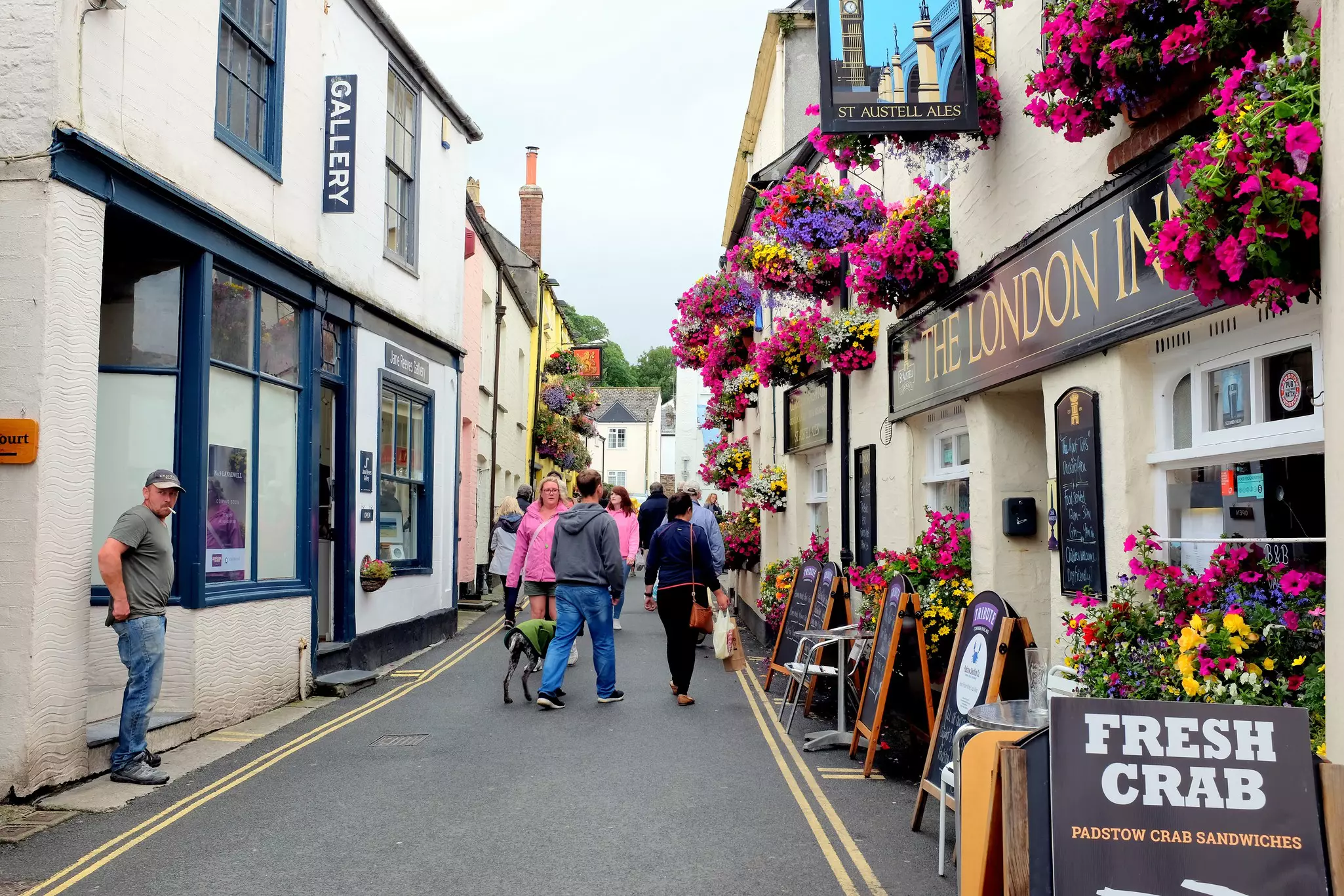 Holidayamkers walking the lanes in admiration of the flowers and architecture at Padstow in Cornwall.