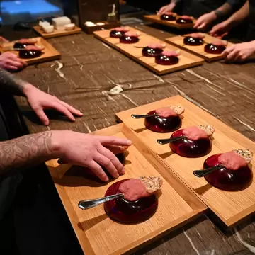 Servers and chefs at a restaurant prepare deluxe dishes for patrons.