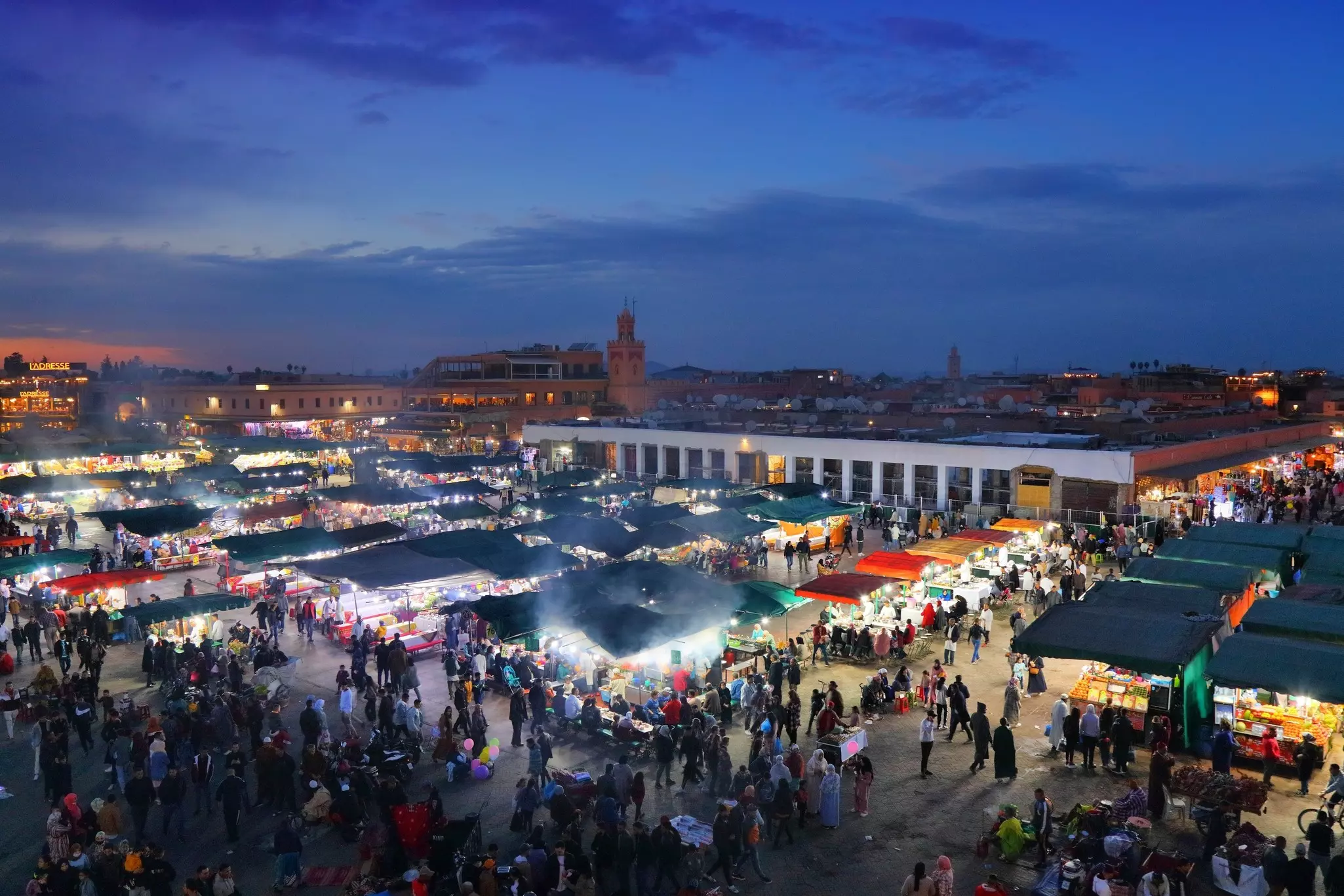 A busy city square with tents lined up in early evening