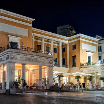 A columned cafe lit at night, bronze lions flanking its steps.