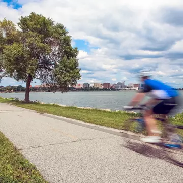 Motion blur of a person riding a bicycle on a lakeside bike path in Madison, Wisconsin with green trees and grass