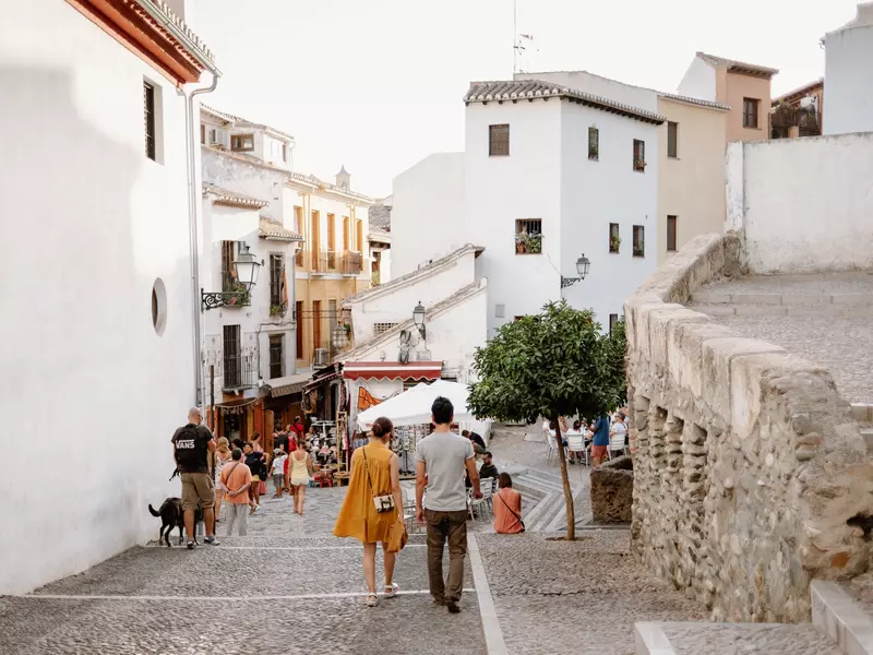 People wander through the white-building-lined streets of the old quarter of Albaicin, Granada.