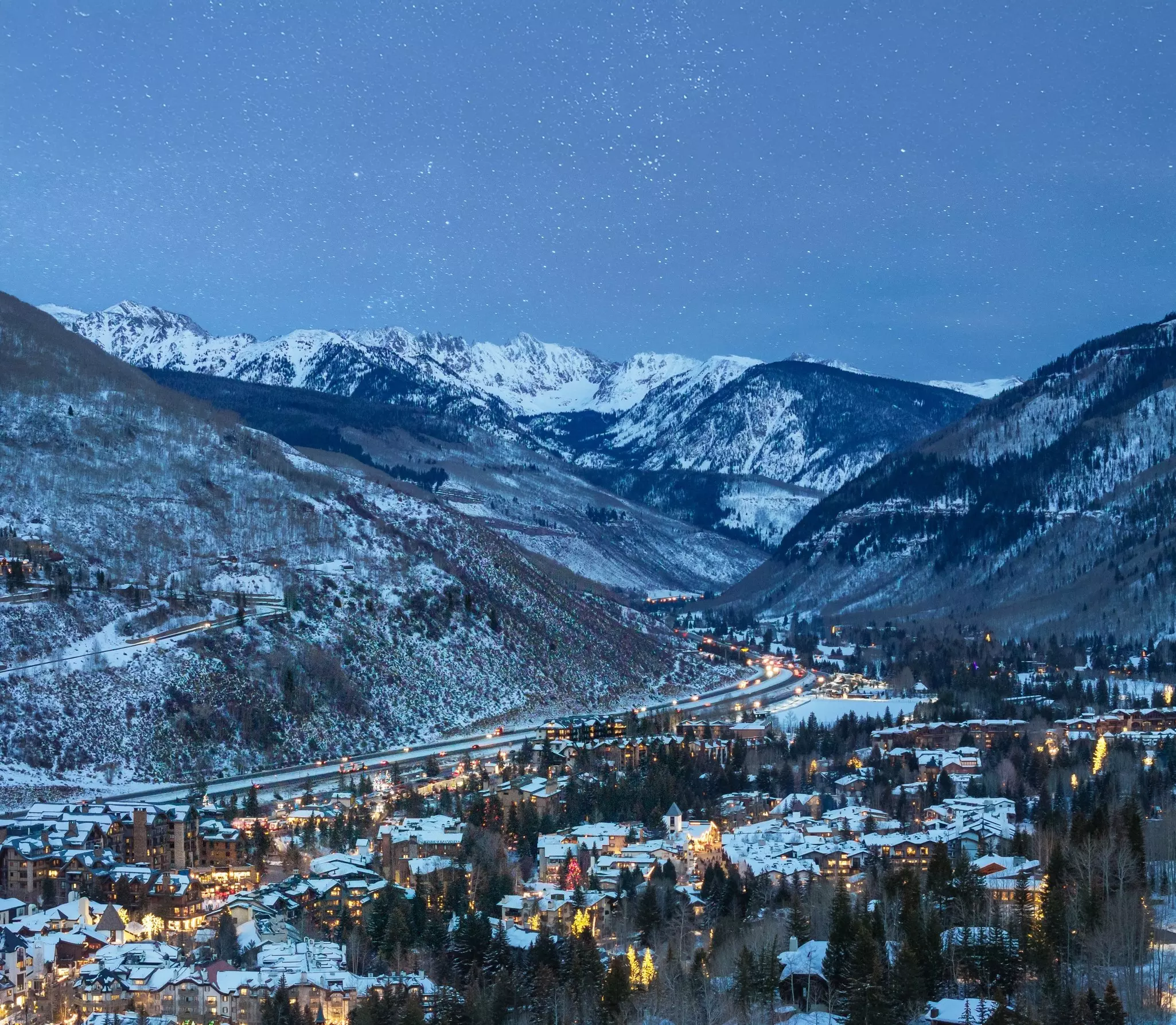 A snow-covered village and a set of mountains at nighttime.