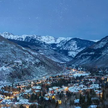A starlit evening with a view of snow-topped homes and mountains in Vail, Colorado.