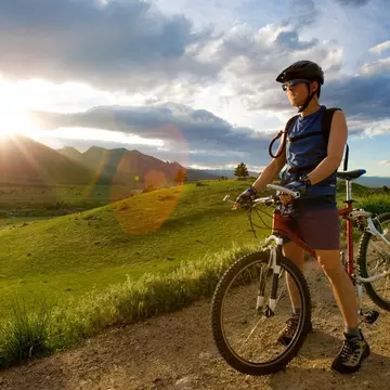 A man standing in a dirt road with a bike